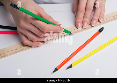 Weibliche Hände mit klassischen French Maniküre zeichnen einen Bleistift mit einem Lineal auf sauber Einheitsblatt Stockfoto