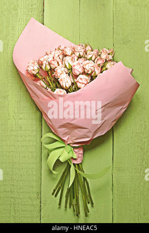 Bouquet von zart rosa Rosen auf dem kleinen grünen hölzernen Hintergrund. Stockfoto