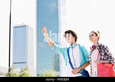 Glückliche Frau stehend mit männlichen Freund ein Taxi in die Stadt Stockfoto