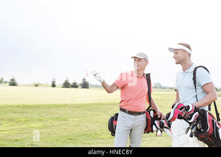 Mann etwas zu Freund am Golfplatz gegen klaren Himmel zeigen Stockfoto