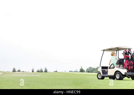 Paar im Golf-Cart gegen klaren Himmel sitzt Stockfoto