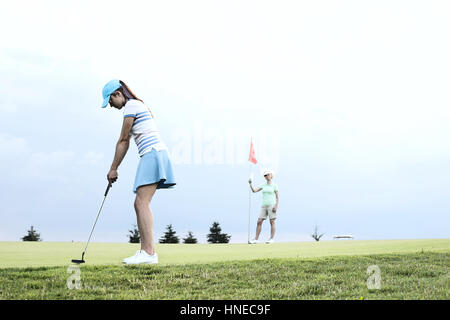 Frau spielt Golf mit Freundin gegen Himmel Stockfoto