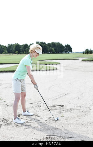 Frau mittleren Alters Golfen am Kurs gegen klarer Himmel Stockfoto