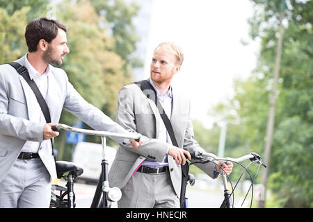 Geschäftsleute sahen einander halten Fahrräder im freien Stockfoto
