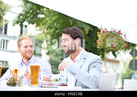 Glücklich Geschäftsleute, die mit Lebensmitteln in Straßencafé Stockfoto