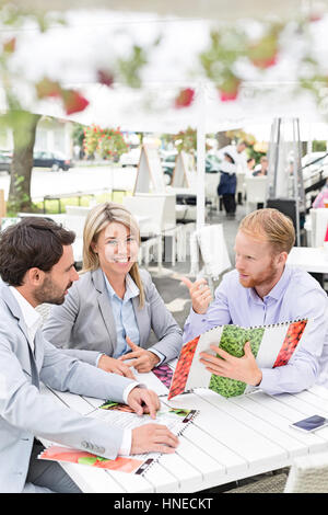 Porträt von glücklich Geschäftsfrau mit männlichen Kollegen Menü im Straßencafé zu entscheiden Stockfoto