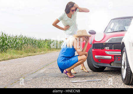 Gespannten Blick auf beschädigte Autos auf der Straße gegen Frauen klarer Himmel Stockfoto