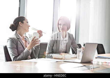 Junge Unternehmerinnen mit Mittagessen am Tisch im Büro Stockfoto