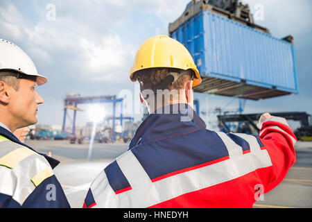 Rückansicht der männlichen Arbeitnehmer im Frachthafen diskutieren Stockfoto