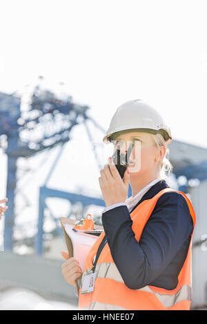 Ingenieurin mit Walkie-talkie im Frachthafen Stockfoto