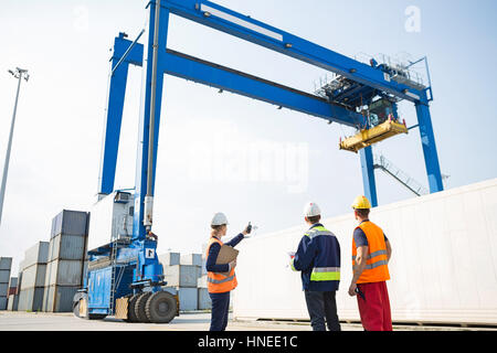 Arbeiter gegen Großkran laden Container am Frachthafen diskutieren Stockfoto