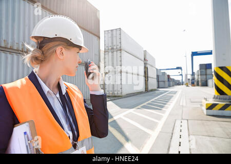 Ingenieurin mit Walkie-talkie im Frachthafen Stockfoto