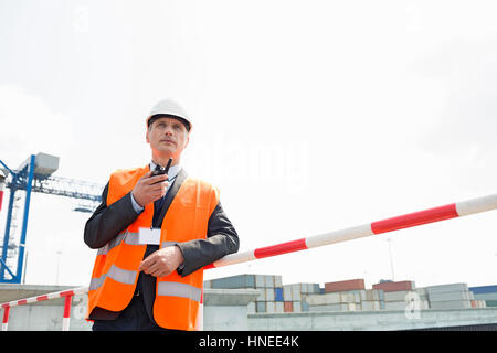 Mann mittleren Alters mit Walkie-talkie im Frachthafen Stockfoto