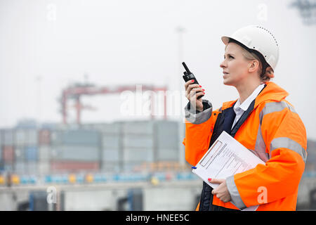 Seitenansicht der Ingenieurin mit Walkie-talkie im Frachthafen Stockfoto