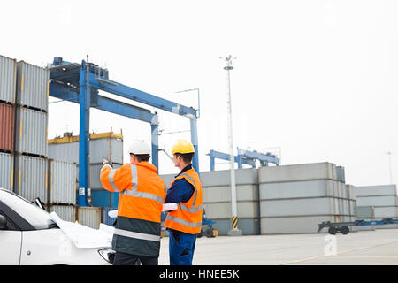 Arbeitnehmer über die Blaupause im Frachthafen diskutieren Stockfoto