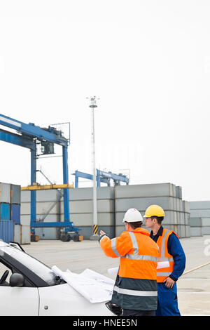 Arbeitnehmer über die Blaupause im Frachthafen diskutieren Stockfoto