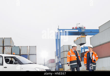 Arbeitnehmer, die während des Gehens im Frachthafen im Gespräch Stockfoto