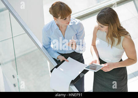 Erhöhte Ansicht Geschäftsfrauen diskutieren über Tablet-PC und Dokumente durch Geländer im Büro Stockfoto