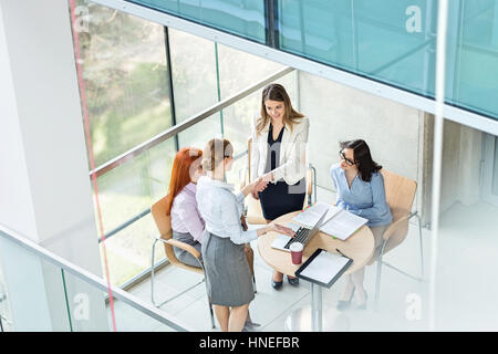 Erhöhte Ansicht Geschäftsfrauen Händeschütteln am Tisch im Büro Stockfoto