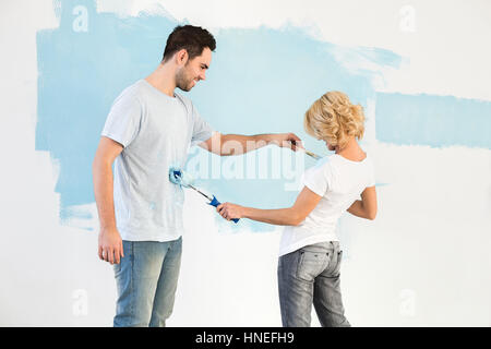 Verspieltes paar malen einander im neuen Haus Stockfoto