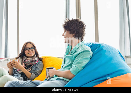 Kaffeetrinken beim Entspannen auf Sitzsäcke in Kreativbüro Geschäftskollegen Stockfoto