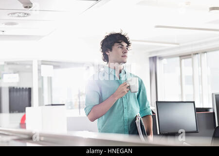 Geschäftsmann, Kaffeetrinken im Kreativbüro mit gedrückter Dateien Stockfoto