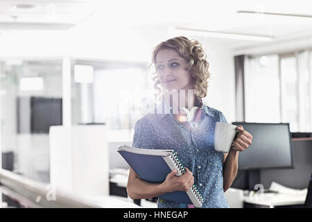 Geschäftsfrau, Kaffeetrinken im Kreativbüro mit gedrückter Dateien Stockfoto