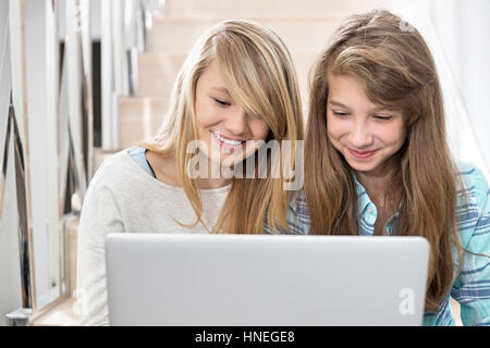 Schwestern mit Laptop auf Treppe Stockfoto