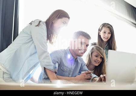 Glückliche Eltern mit Töchtern mit Laptop zu Hause Stockfoto