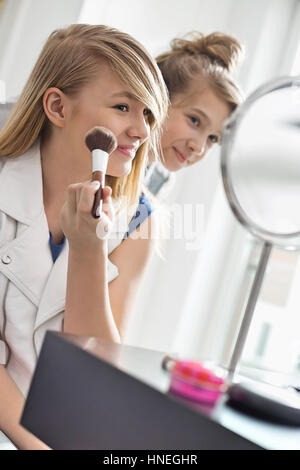Mädchen beobachten Schwester beim Schminken vor dem Spiegel zu Hause Stockfoto