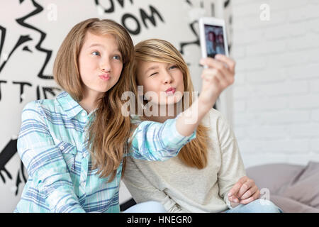 Nette Schwestern schmollend beim Fotografieren mit Ihrem Smartphone zu Hause Stockfoto