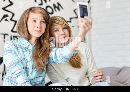 Nette Schwestern fotografieren mit Ihrem Smartphone zu Hause Stockfoto