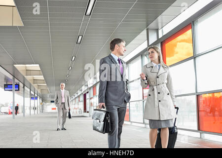 Unternehmer und Unternehmerin im Gespräch während des Gehens im Bahnhof Stockfoto