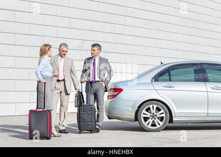 Geschäftsleute mit Gepäck auf Straße außen Auto diskutieren Stockfoto