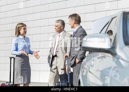 Geschäftsleute mit Gepäck außerhalb Auto diskutieren Stockfoto