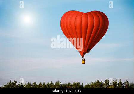 Roten Luftballon in der Form eines Herzens in blauen Himmel fliegen Stockfoto