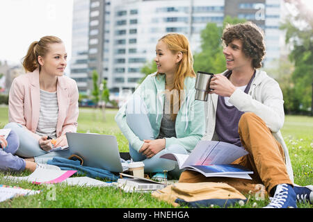Junger Mann mit Kaffee während des Studiums mit Freundinnen am College campus Stockfoto