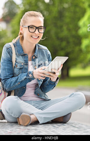 In voller Länge Portrait von lächelnden jungen weiblichen College-Student mit Tablet PC im park Stockfoto