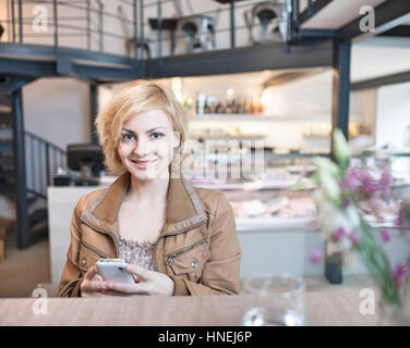 Porträt der fröhliche junge Frau mit Handy im café Stockfoto