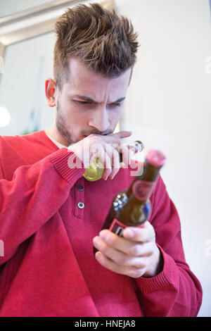 Junger Mann lesen Etikett Bierflasche im café Stockfoto