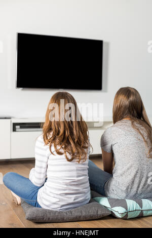 Rückansicht der Schwestern zu Hause vor dem Fernseher Stockfoto