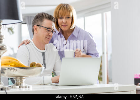 Älteres Paar mit Laptop zusammen am Tisch im Haus Stockfoto