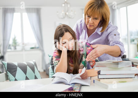 Studium zu Hause gelangweilt Mädchen bei Mutter Stockfoto