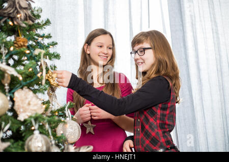 Schwestern, die Dekoration am Weihnachtsbaum zu Hause Stockfoto