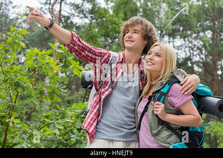 Junge männliche Wanderer zeigt etwas zu Frau im Wald Stockfoto