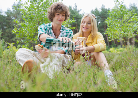 Junge männliche Wanderer Kaffee für Frau beim Entspannen im Bereich gießen Stockfoto