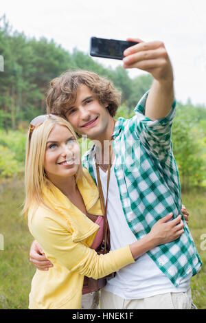 Glückliches junges Paar unter Selbstportrait durch Handy im Bereich Stockfoto