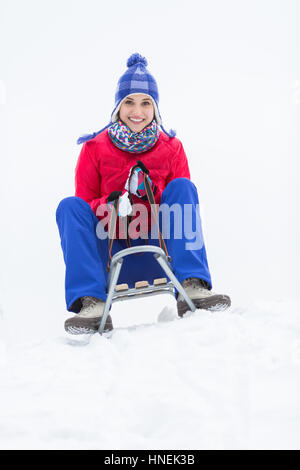 In voller Länge Portrait von glückliche junge Frau Schlittenfahrt im Schnee genießen Stockfoto