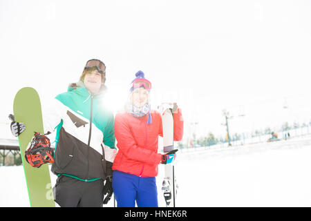 Junges Paar mit Snowboard und Ski im Schnee Stockfoto