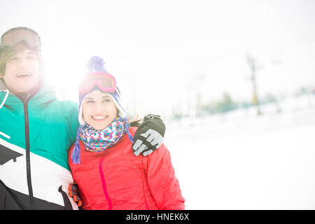Fröhliches junges Paar stehende Arm um im Schnee Stockfoto